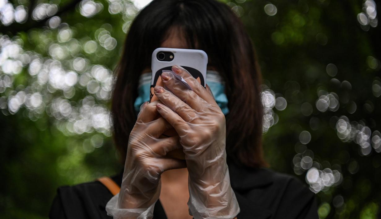 Seorang warga mengenakan masker dan sarung tangan menunggu dalam barisan untuk tes virus corona di lingkungan di Wuhan, provinsi Hubei, Jumat (15/5/2020). Pihak berwenang Kota Wuhan menggelar tes massal terhadap 11 juta warganya untuk mencegah gelombang kedua pandemi Covid-19. (Hector RETAMAL/AFP)