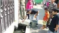 Warga Duren Sawit, Jakarta Timur lepas ratusan ikan kecil di selokan demi cegah demam berdarah. (Liputan6.com/Nanda Perdana Putra)