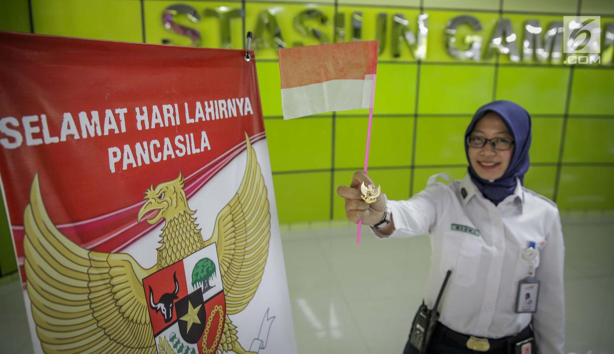 Petugas PT KAI DAOP 1 menunjukan pin garuda di Stasiun Gambir, Jakarta, Kamis (1/6). Dalam rangka memperingati HUT Pancasila PT KAI Daop 1memberikan pin dan bendera merah putih kepada penumpang kereta api. (Liputan6.com/Faizal Fanani)