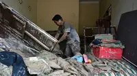 Desa Garoga dilaporkan "hilang" dan berganti menjadi hamparan lumpur, batu, serta sampah potongan dan batang kayu pohon. Tampak dalam foto, seorang warga mengumpulkan barang-barangnya dari rumahnya yang rusak akibat banjir bandang di Garoga, Provinsi Sumatera Utara, pada Kamis 4 Desember 2025. (YT HARIONO/AFP)