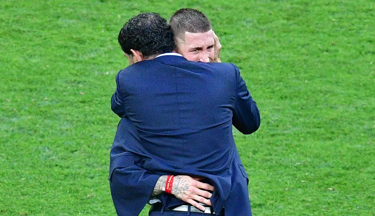 Pelatih Spanyol, Fernando Hierro memeluk bek Sergio Ramos yang menangis usai pertandingan melawan Rusia di babak 16 besar Piala Dunia 2018 di Stadion Luzhniki, Moskow, Rusia (1/7). Spanyol kalah lewat adu penalti atas Rusia 3-4. (AFP Photo/Mladen Antonov)
