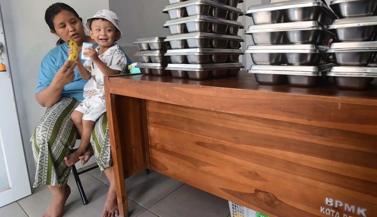 Ibu dan anaknya mengambil makan bergizi gratis (MBG)  di Posyandu kawasan Limo, Depok, Jawa Barat, Selasa (14/7/2025).