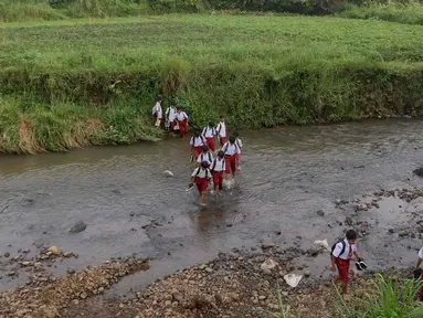 Sejumlah pelajar Sekolah Dasar (SD) menyeberangi sungai Cihideung untuk menuju sekolah mereka di Kampung Sempur, Kabupatan Bogor, Jawa Barat, Selasa (15/4/2025). (Liputan6.com/Herman Zakharia)