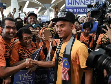 Pesepak bola Malaysia, Faiz Subri, disambut warga negeri jiran saat tiba di Bandara International Kuala Lumpur, Malaysia, Rabu (11/1/2017). Pemain Penang FA ini menjadi pesepak bola Asia pertama yang meraih FIFA Puskas Award. (AFP/Mohd Rasfan)