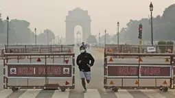 Seorang pria India berlari mengenakan masker pada pagi hari di tengah kabut tipis di New Delhi, India (28/10/2019). Menurut pemerintah New Delhi kualitas udara buruk setelah festival Hindu Diwali tahun ini masih lebih baik daripada tiga tahun terakhir. (AP Photo/Manish Swarup)