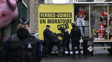 Petugas polisi Prancis saat berada di lokasi di mana para aktivis Greenpeace yang memblokir jalan dengan sebuah trailer saat demonstrasi menentang kebijakan pertanian dan mengecam dampak ekologis dari pertanian industri, di dekat Kementerian Pertanian di Paris, pada tanggal 20 November 2023. (Miguel MEDINA/AFP)