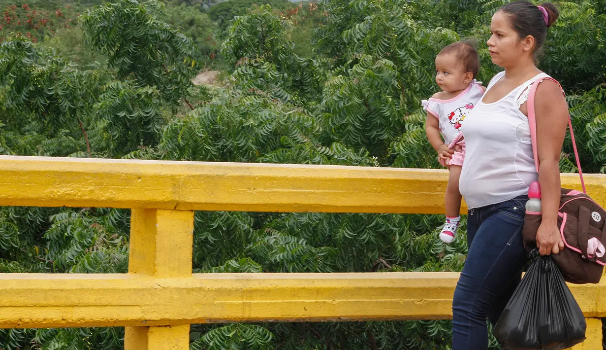 Perempuan Venezuela menenteng bahan makanan yang dibeli di Kolombia, ketika berjalan pulang menuju perbatasan di Cucuta, Rabu (6/7). Krisis ekonomi yang melanda Venezuela membuat warga menerobos perbatasan masuk ke wilayah Kolombia (Schneyder MENDOZA/AFP)