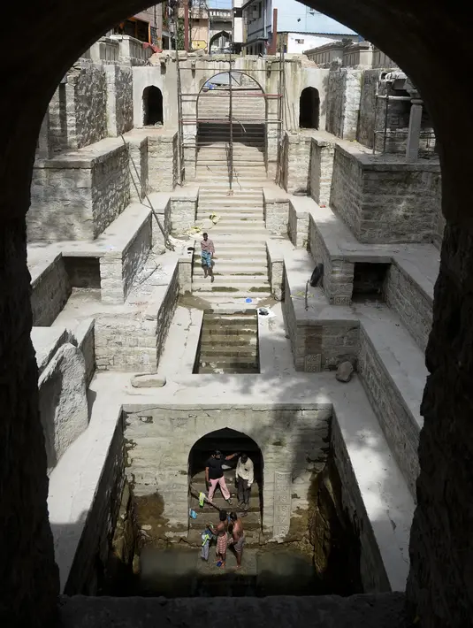 Orang-orang mandi di sumur tangga Bansilalpet berusia abad ke-18 yang sedang menjalani pekerjaan restorasi di Secunderabad, kota kembar Hyderabad, India (24/8/2022). (AFP/Noah Seelam)