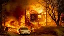 Sebuah rumah dan mobil dilalap api saat kebakaran Dixie berkobar di Greenville, California, Amerika Serikat, 5 Agustus 2021. Kebakaran hutan terbesar di California telah meluluhlantahkan kota, merusak lampu jalan, dan menghancurkan bangunan bersejarah. (JOSH EDELSON/AFP)