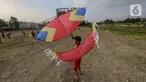 Seorang anak bersiap menerbangkan layangan koang di lahan kosong Kampung Sawah, Ciputat, Tangerang Selatan, Selasa (2/6/2020). Masa pembatasan sosial berskala besar selama pandemi Covid-19 tidak menyurutkan anak-anak bermain layangan koang meski tanpa menggunakan masker. (Liputan6.com/Fery Pradolo)