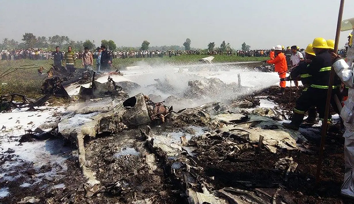Petugas pemadam berupaya menjinakkan api dari puing-puing pesawat militer berukuran kecil yang jatuh sesaat setelah lepas landas di bandara Kota Naypidaw, Myanmar, Rabu (10/2). Sedikitnya empat orang tewas dalam kecelakaan ini. (AFP/PHOTO/AUNG Htet)