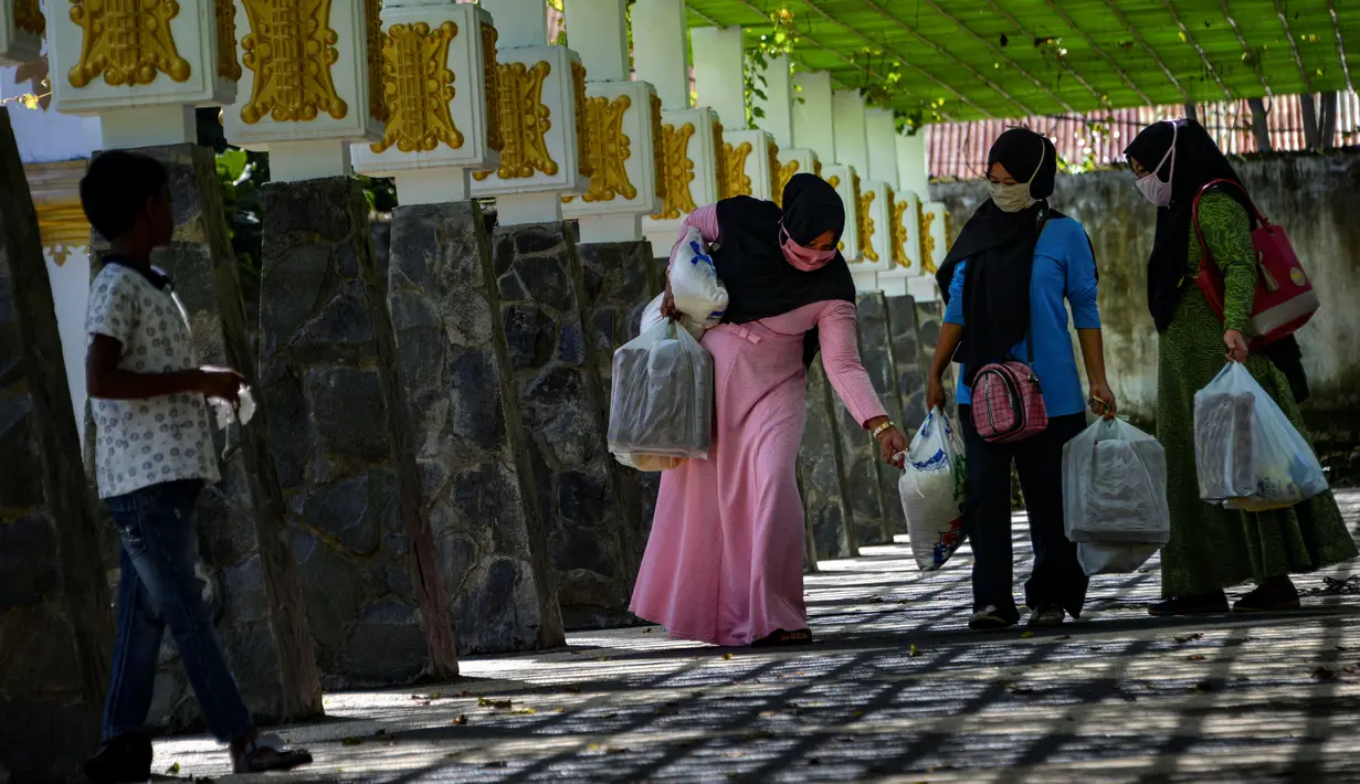 Warga usai membeli sembako murah di Banda Aceh, Aceh, Kamis (14/5/2020). Di tengah pandemi virus corona COVID-19, hadirnya penjualan sembako murah sangat membantu sebagian warga untuk memenuhi kebutuhan hidup. (CHAIDEER MAHYUDDIN/AFP)