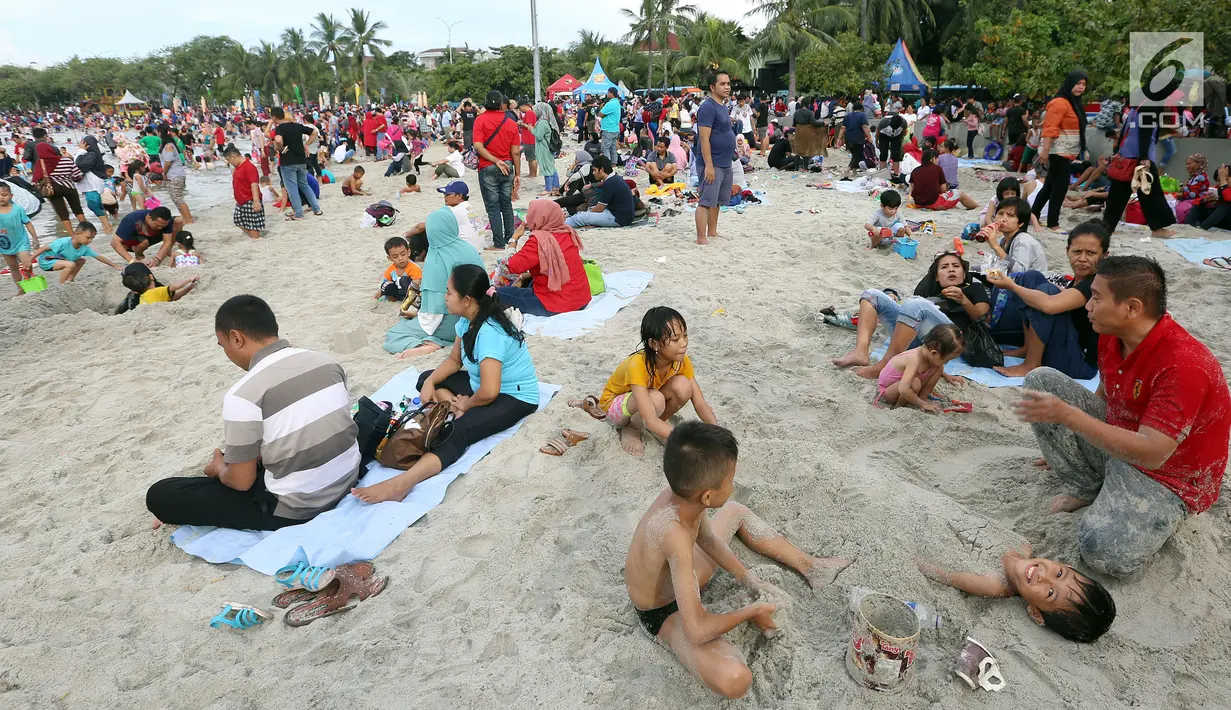 Sejumlah pengunjung bermain pasir di Pantai Ancol, Jakarta, Senin (26/6). Memasuki hari kedua lebaran Warga memanfaatkan liburnya bersama keluarga bertamasya ke tempat-tempat wisata yang ada di Jakarta kususnya Ancol. (Liputan6.com/Johan Tallo)