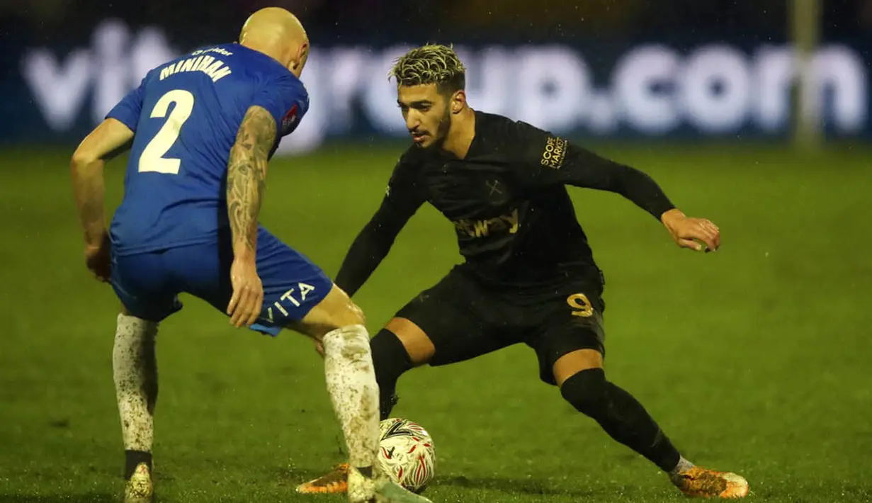 Pemain Stockport County, Sam Minihan, berebut bola dengan pemain West Ham United, Said Banrahma, pada laga Piala FA di Stadion Edgeley Park, Senin (11/1/2021). West Ham United menang dengan skor tipis 1-0. (Clive Brunskill/Pool via AP)