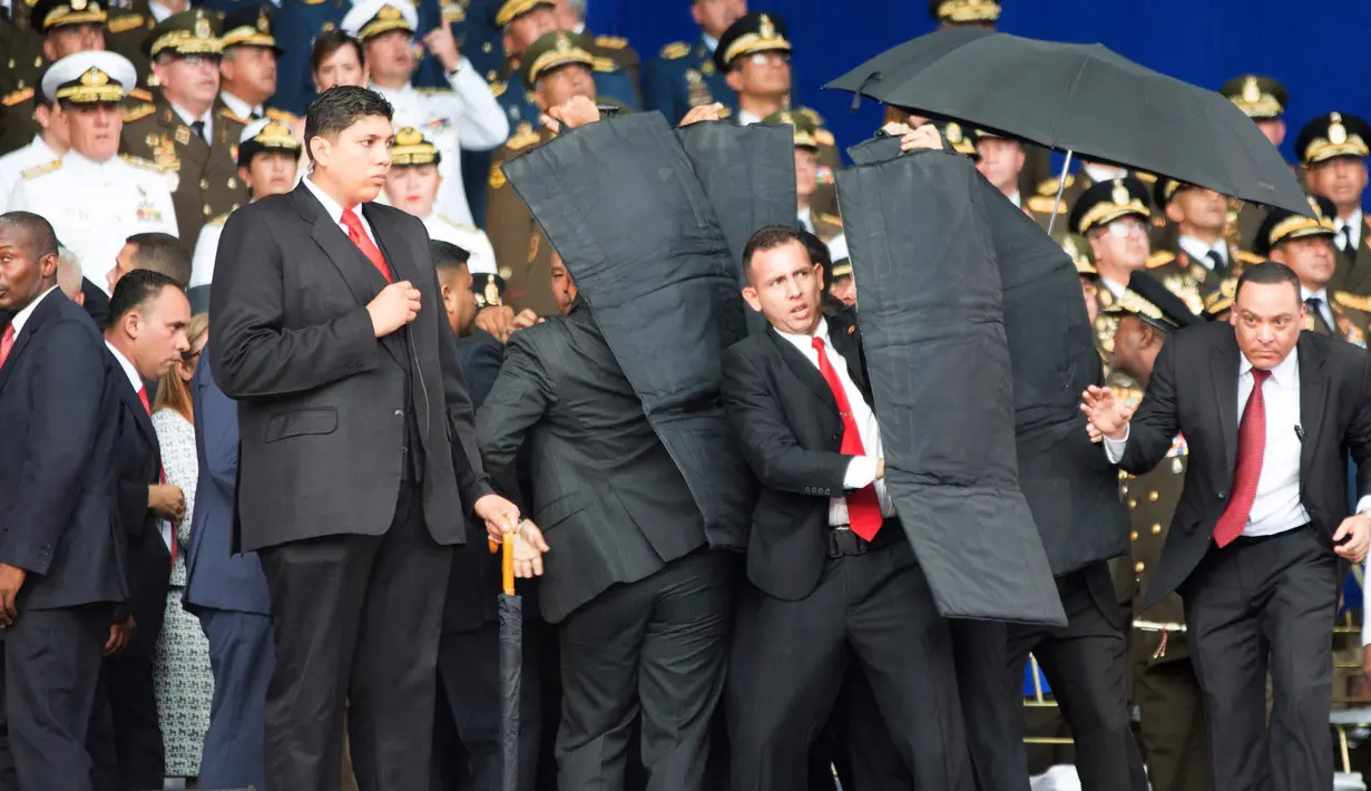 Pengawal melindungi Presiden Venezuela Nicolas Maduro dengan perisai antipeluru saat serangan drone di Caracas, Venezuela, Sabtu (4/8). Serangan terjadi saat Presiden Maduro berpidato dalam HUT ke-81 Tentara Venezuela. (Xinhua via AP)