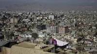 Seorang wanita menjemur pakaiannya di atap yang menghadap kota Kabul di Kabul, Afghanistan (28/11/2019). Puluhan ribu warga Afghanistan yang terlantar secara internal tinggal di kamp-kamp, yang kekurangan fasilitas dasar, di Afghanistan. (AP Photo/Altaf Qadri)