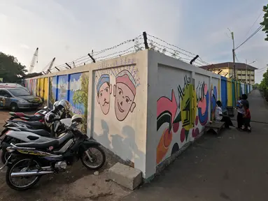 Aktivitas warga di dekat mural Betawi yang berada di Kampung Pitung, Marunda, Jakarta, Senin (2/7). Mural-mural bernuansa Betawi kini menghiasi destinasi wisata rumah dan masjid Pitung. (Merdeka.com/Iqbal S. Nugroho)