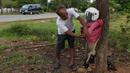 Seorang pria mendirikan orang-orangan sawah di depan rumahnya di provinsi Kampong Cham, Kamboja, 11 Oktober 2020. Penduduk di desa itu menggunakan orang-orangan sawah atau disebut juga Tim Mong untuk menangkal virus corona  Covid-19 berdasarkan kepercayaan yang mereka yakini. (TANG CHHIN Sothy/AFP)