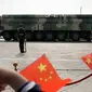 Warga mengibarkan bendera China saat kendaraan militer yang membawa Dongfeng-41 atau DF-41 melintas dalam parade militer di Beijing, 1 Oktober 2019. Rudal balistik antarbenua DF-41 menjadi sorotan pengamat dan ahli persenjataan dunia karena disebut dapat menjangkau wilayah AS. (AP/Mark Schiefelbein)