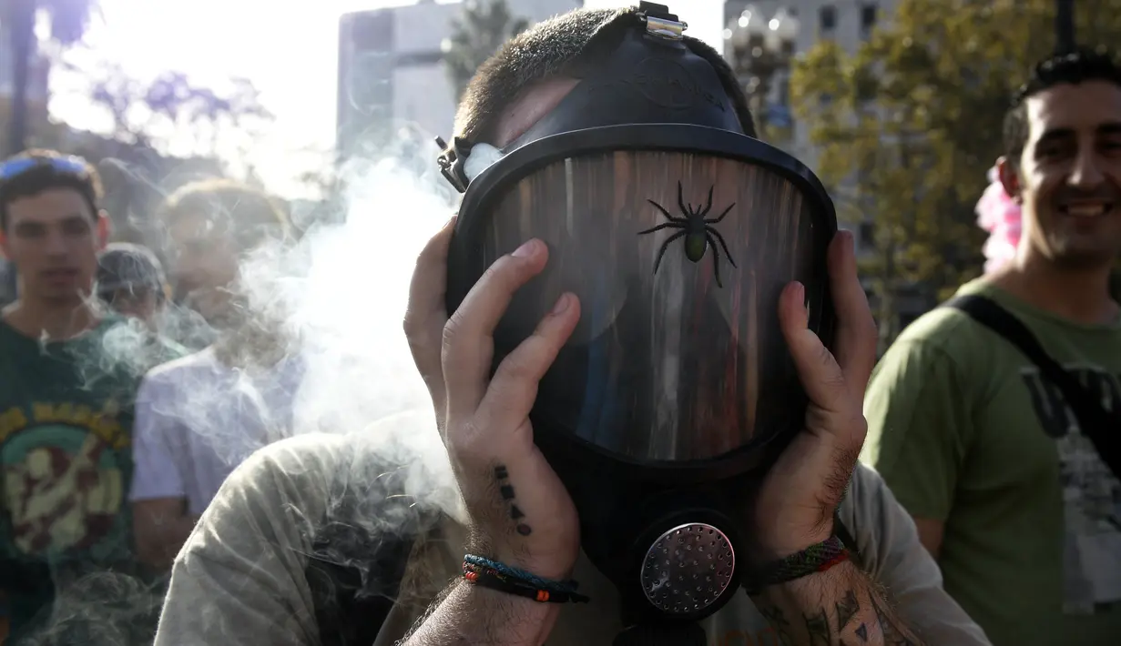 Seorang pria mengisap ganja menggunakan masker di alun-alun Plaza de Mayo selama pawai dunia untuk undang-undang mariyuana di Buenos Aires, Argentian (6/5).(AFP Photo/Juan Mabromata)