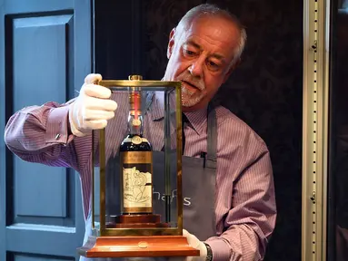Seorang porter Bonhams menunjukkan botol wiski Macallan Valerio Adamai 1926 pada lelang di Edinburgh, Skotlandia, Rabu (3/10). Botol berusia 60 tahun itu menjadi botol wiski termahal di dunia setelah terjual seharga RP16,7 miliar. (AFP/Andy Buchanan)