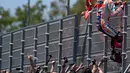 Pembalap Repsol Honda, Marc Marquez memanjat pagar lintasan setelah berhasil menjadi yang terdepan saat menjalani balapan MotoGP Spanyol 2018 di Sirkuit Jerez, Minggu (6/5). Marquez mengukir waktu 41 menit 39,678 detik. (AFP Photo/ JAVIER SORIANO)