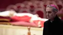 Jenazah mendiang Paus Emeritus Benediktus XVI disemayamkan saat Pastor Georg Gaenswein berdiri di sebelah kanan di Basilika Santo Petrus, Vatikan, Senin (2/1/2023). Benediktus XVI, teolog Jerman yang akan dikenang sebagai paus pertama dalam 600 tahun yang mengundurkan diri, telah meninggal pada 31 Desember 2022 di usia 95 tahun. (AP Photo/Andrew Medichini)