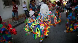Sejumlah orang menari sambil mengenakan kostum berwarna-warni dan topeng saat perayaan tradisional di Naiguata, Venezuela (31/5). Dalam festival ini peserta kerasukan dan menari. (AP/Arian Cubillos)