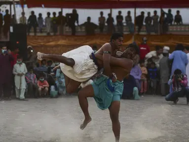 Pegulat bertarung selama turnamen gulat tradisional Sindhi Malakhra di kota pelabuhan Karachi, Pakistan pada Minggu (13/12/2020). Gulat kuno yang dimulai sejak 5.000 tahun lalu ini salah satu olahraga favorit di kalangan pria. (Photo by Asif HASSAN / AFP)