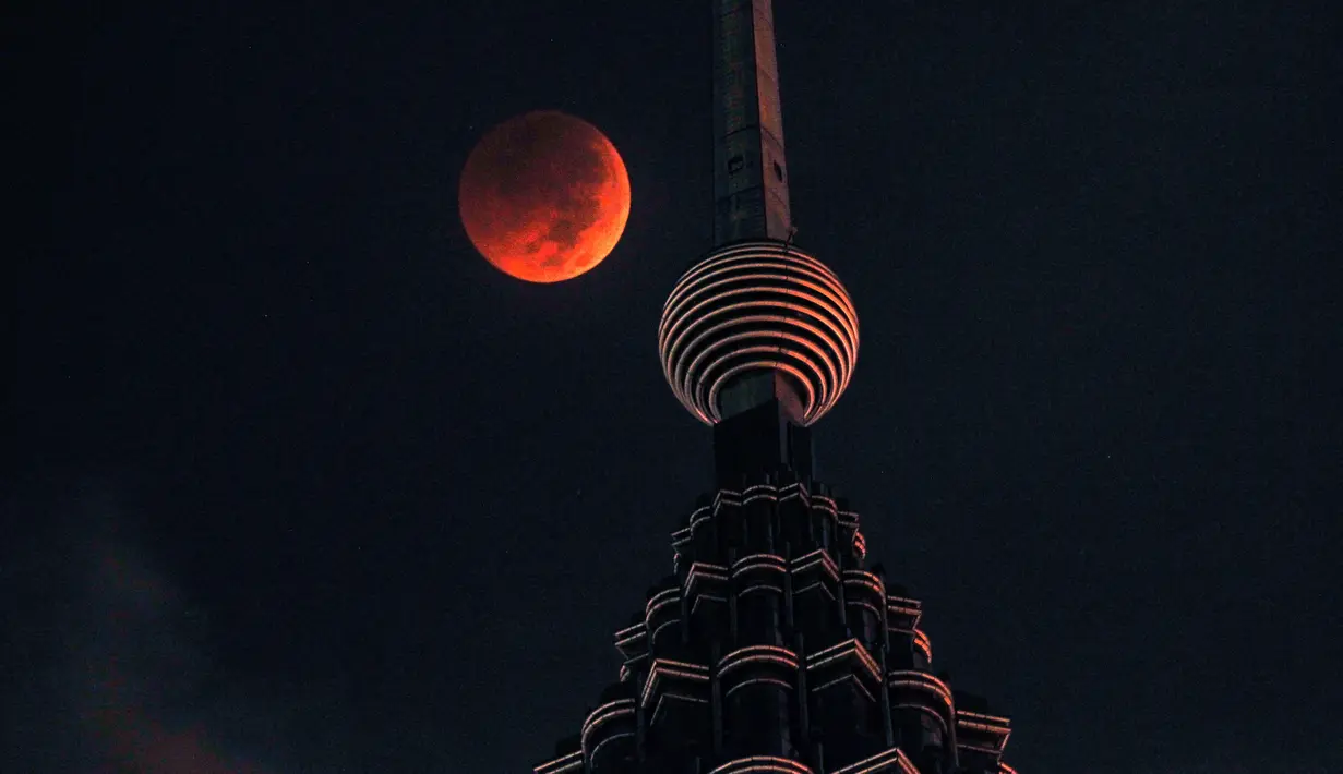 Bulan berwarna merah darah terlihat di atas Menara Petronas saat terjadinya fenomena gerhana bulan total  di Kuala Lumpur, Malaysia, Sabtu (28/7). Gerhana bulan terlama pada abad ini dapat disaksikan di seluruh dunia dengan mata telanjang. (AP/Yam G-Jun)
