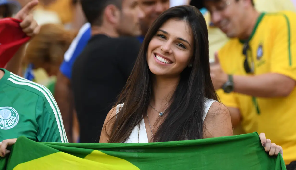 Seorang fans cantik asal Brasil tersenyum manis saat menonton semifinal sepak bola antara Brasil melawan Honduras pada ajang Olimpiade Rio 2016 di Stadion Maracana, Rio de Janeiro, Brasil, (17/8/2016). (AFP/Martin Bernetti)