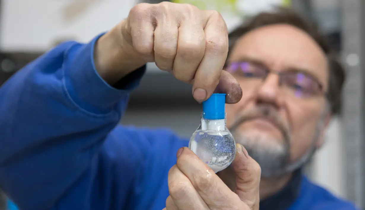 Pemilik perusahaan Original Vienna Snow Globes, Erwin Perzy III merakit bola salju yang berisi gulungan kertas toilet di Wina, Austria, pada 17 April 2020. Bola salju yang memiliki desain istimewa ini terinspirasi dari panic buying pada awal virus corona Covid-19. (ALEX HALADA/AFP)