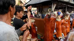 Pedagang menyiapkan babi panggang di pasar di Phnom Penh, Kamboja (4/2). Menyambut Tahun Baru Imlek, warga Kamboja mempersiapkan daging babi panggang untuk sajian makan. (AFP Photo/Tang Chhin Sothy)