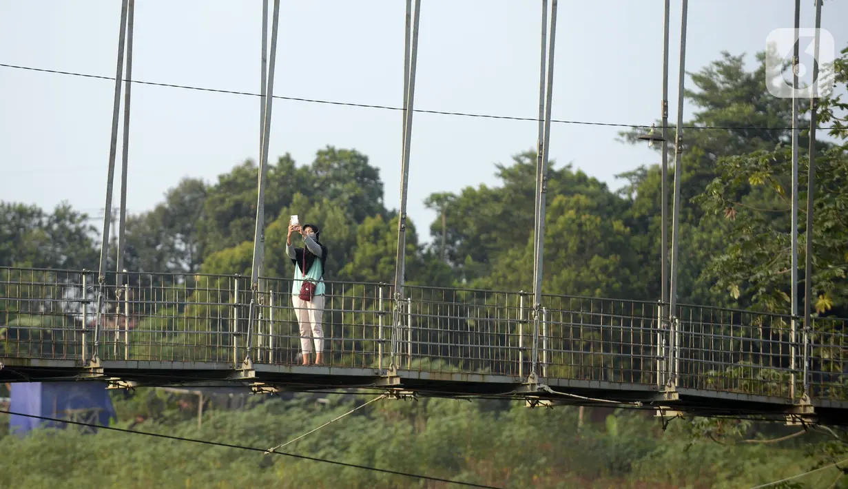 Warga asyik berswafoto di atas jembatan gantung, Kelurahan Curug, Bojongsari, Kota Depok, Jawa Barat, Senin (24/8/2020). Setiap sore, warga sekitar bermain di jembatan tersebut sambil menikmati matahari tenggelam. (merdeka.com/Dwi Narwoko)