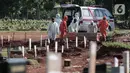 Petugas Suku Dinas Pertamanan dan Pemakaman membawa jenazah pasien COVID-19 untuk dimakamkan di TPU Pondok Rangon, Jakarta, Rabu (17/6/2020).  Tercatat ada penambhan 1.031 orang total kasus hingga Rabu (17/6/2020) pukul 12.00 WIB sebanyak 41.431 orang. (Liputan6.com/Johan Tallo)