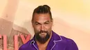 Jason Momoa berpose dengan boneka babi saat menghadiri pemutaran perdana film Netflix "Slumberland" di AMC Century City di Century City, California pada 9 November 2022. Bintang Aquaman itu juga mengenakan celana berkaki lebar yang serasi.  (Jon Kopaloff/Getty Images/AFP)