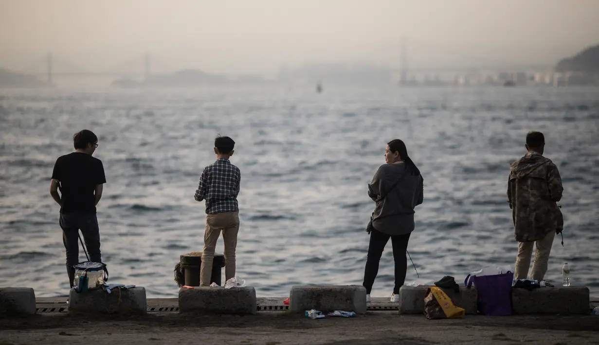 Orang-orang memancing di Pelabuhan Victoria di Hong Kong (3/3). Pelabuhan Victoria adalah sebuah pelabuhan bentang alam alami yang terletak antara Pulau Hong Kong dan Kowloon di Hong Kong. (AFP Photo/Dale De La Rey)