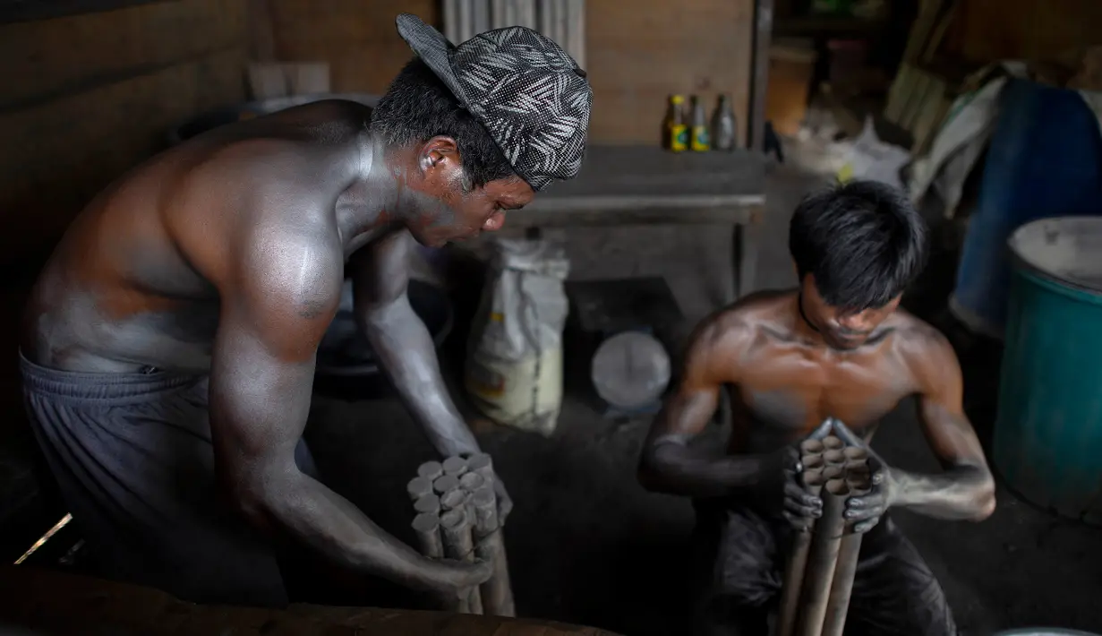 Dua pekerja memasukan bubuk mesiu ke dalam selongsong saat membuat kembang api untuk perayaan Tahun Baru 2019 di Bocaue, Bulacan, Manila Utara (26/12). (AFP Photo/Noel Celis)