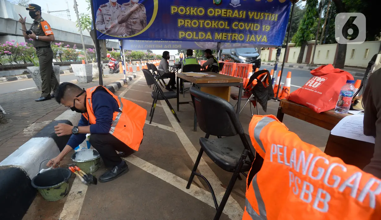 Petugas Satpol PP memberikan sanksi sosial mengcat pembatas jalan kepada warga pelanggar karena tidak menggunakan masker di Lebak Bulus, Jakarta, senin (14/09/2020). Pemerintah Provinsi DKI Jakarta memperketat kembali PSBB karena kasus Covid-19 terus mengalami peningkatan. (merdeka.com/Dwi Narwoko)