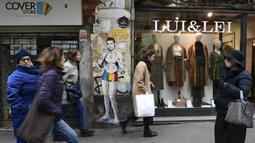 Sejumlah warga melintasi mural dengan gambar bintang Juventus, Cristiano Ronaldo, yang terdapat di Milan, Senin (19/3). Mural berjudul Cristiano's Secret ini karya seniman Italia, TvBoy. (AFP/Miguel Medina)