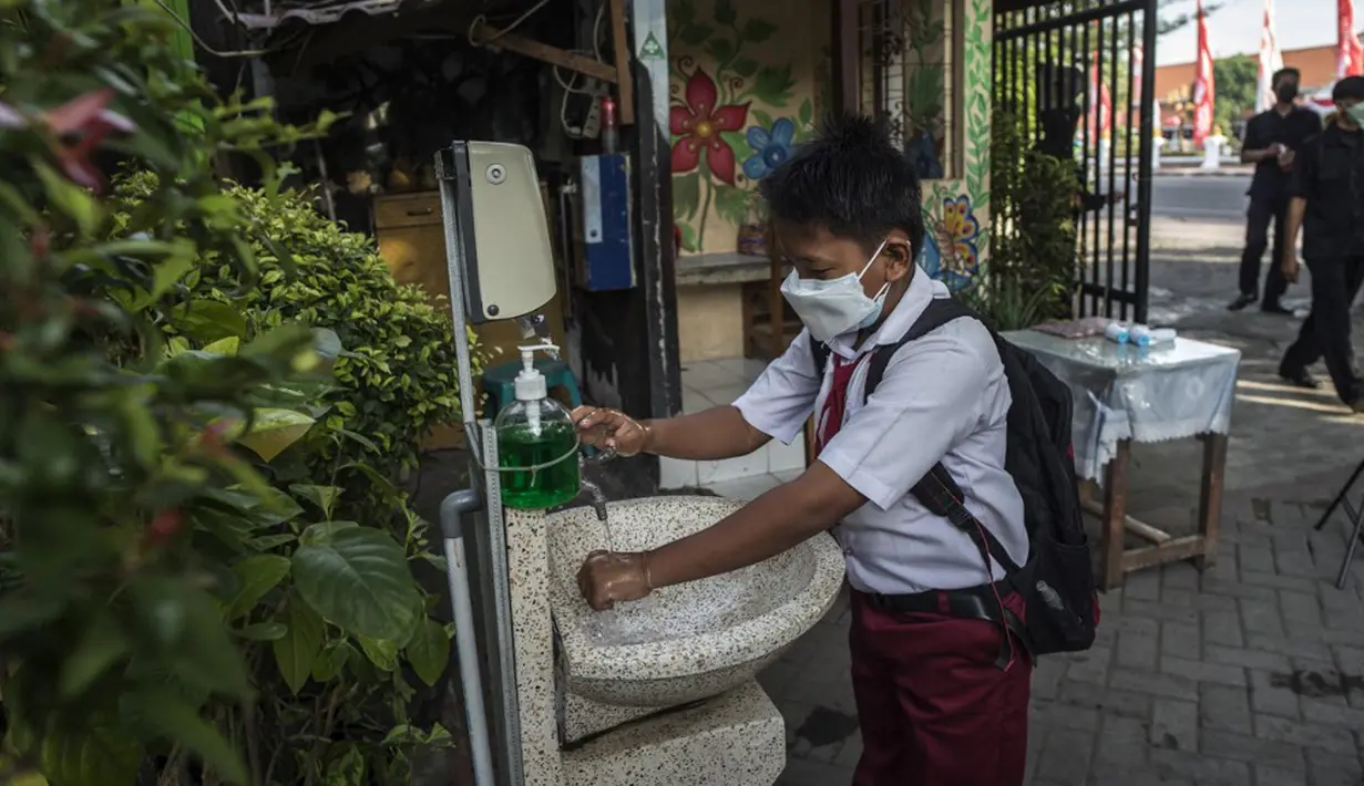 Seorang siswa mencuci tangan sebelum memasuki sekolah sebelum mengikuti pembelajaran tatap muka (PTM) di sebuah sekolah di Surabaya, Jawa Timur, Senin (6/9/2021). Pemerintah kembali membuka sekolah di tengah pandemi COVID-19. (JUNI KRISWANTO/AFP)