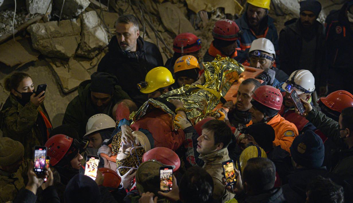 Petugas penyelamat mengangkat tandu yang membawa Seher, seorang gadis Suriah berusia 15 tahun di Hatay, tenggara Turki, pada 14 Februari 2023. Saher berhasil diselamatkan setelah terperangkap di bawah reruntuhan selama 210 jam seminggu setelah gempa mematikan melanda sebagian dari Turki dan Suriah. (AFP/Yasin AKGUL)