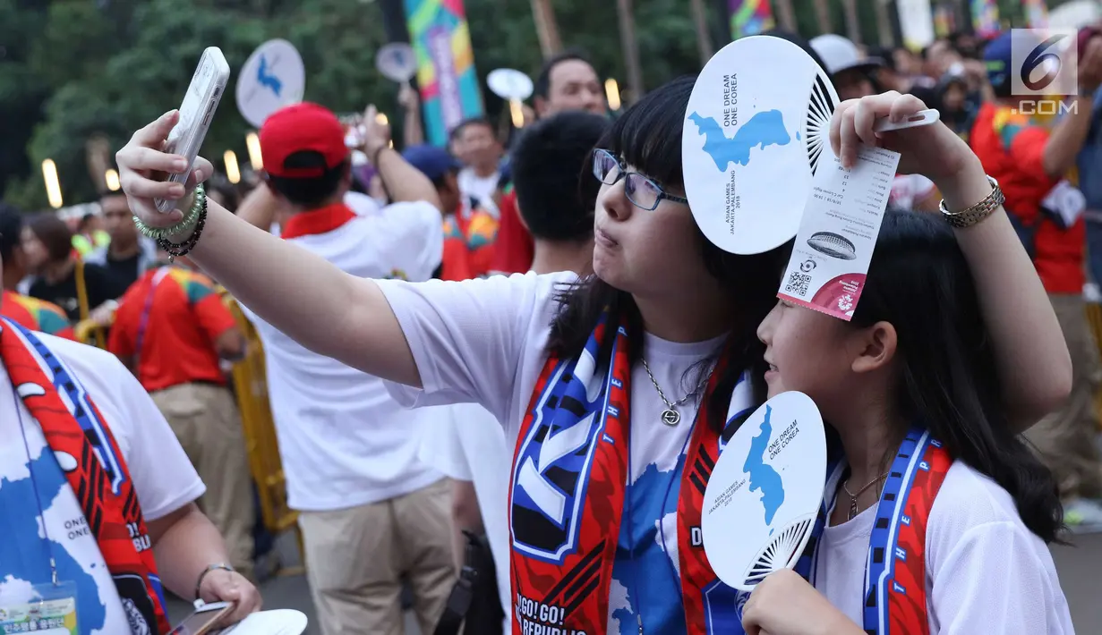 Pendukung tim Korea Bersatu berswafoto jelang menyaksikan seremoni pembukaan Asian Games 2018 di Stadion GBK, Jakarta, Sabtu (18/8). Asian Games 2018 akan berlangsung hingga 2 September, mendatang. (Liputan6.com/Helmi Fithriansyah)