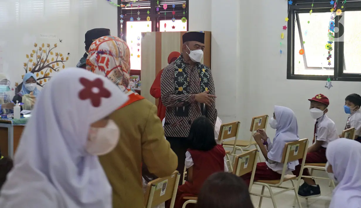 Menko PMK Muhadjir Effendy menyapa para siswa saat meninjau vaksinasi COVID-19 di SDN 01 Depok, Depok, Jawa Barat, Selasa (14/12/2021). Kunjungan tersebut untuk melihat persiapan vaksinasi COVID-19 anak usia 6-11 tahun yang dilaksanakan mulai hari ini. (Liputan6.com/Herman Zakharia)