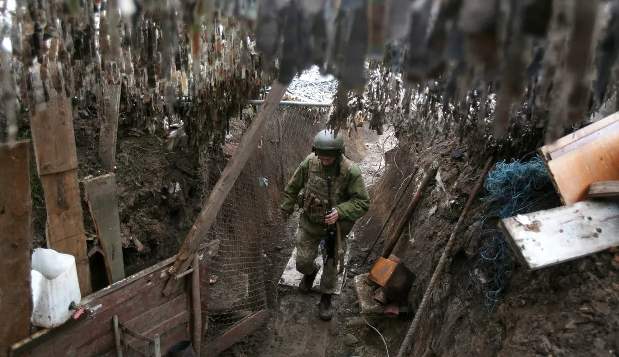 Seorang prajurit Ukraina berjalan di sepanjang parit di posisi garis depan dengan separatis yang didukung Rusia dekat Gorlivka, Donetsk, Ukraina, 14 April 2021. (STR/AFP)