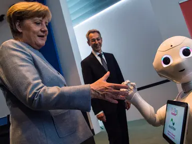 Kanselir Jerman Angela Merkel disapa robot interaktif di stand digitalSTROM selama pameran Girl's Day di Berlin, Rabu (26/4). Pameran ini bertujuan menarik wanita muda untuk menggeluti pekerjaan hi-tech dan engineering. (AFP PHOTO / John MACDOUGALL)