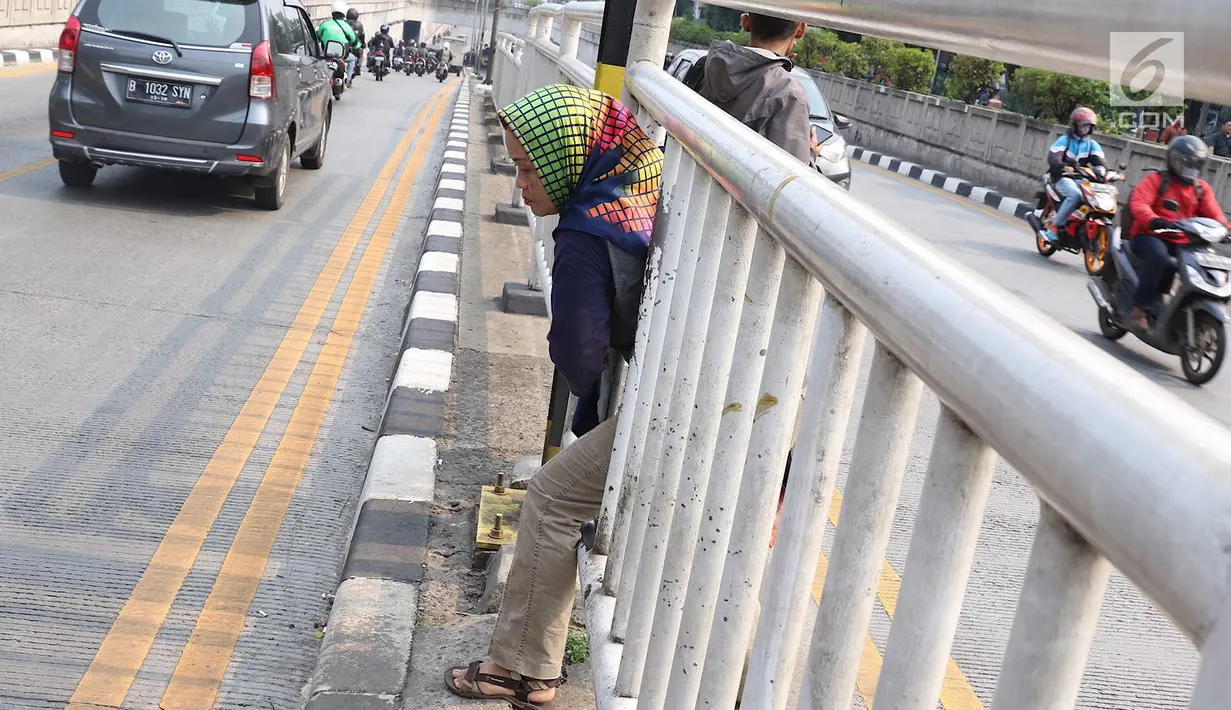 Seorang wanita menerobos pagar pembatas jalan di kawasan Pasar Minggu, Jakarta, Kamis (5/4). Kondisi Jembatan Penyeberangan Orang (JPO) yang tak kunjung diperbaiki membuat warga nekat menyeberang lewat celah pagar pembatas (Liputan6.com/Immanuel Antonius)