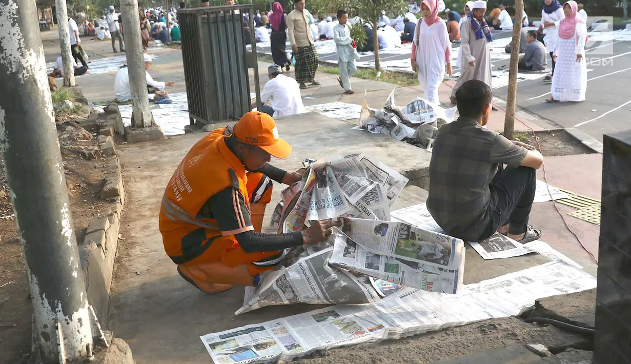 Petugas kebersihan memungut koran usai salat id Hari Raya Idul Fitri 1 Syawal 1439 H di kawasan Senen, Jakarta, Jumat (15/6). Banyaknya koran berserakan membuat petugas harus sigap membersihkan agar tidak mengotori jalan. (Liputan6.com/Immanuel Antonius)
