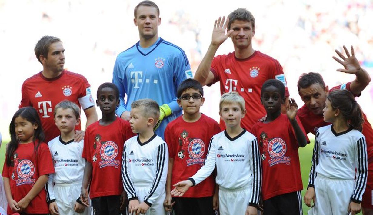 Pemain Bayern Muenchen Philipp Lahm, Manuel Neuer dan Thomas Mueller berfoto dengan anak-anak pengungsi (kaos merah) sebelum melawan FC Augsburg dalam lanjutan Liga Jerman. Sabtu (12/9/2015). (AFP Photo/DPA/Anandreas Gebert)