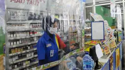 Pekerja melayani pembeli dari balik plastik pembatas pada sebuah minimarket di kawasan Cinere, Depok, Jawa Barat, Rabu (8/4/2020). Penggunaan plastik pembatas tersebut bertujuan untuk mengantisipasi penyebaran virus corona atau COVID-19 sebagai bentuk social distancing. (merdeka.com/Arie Basuki)